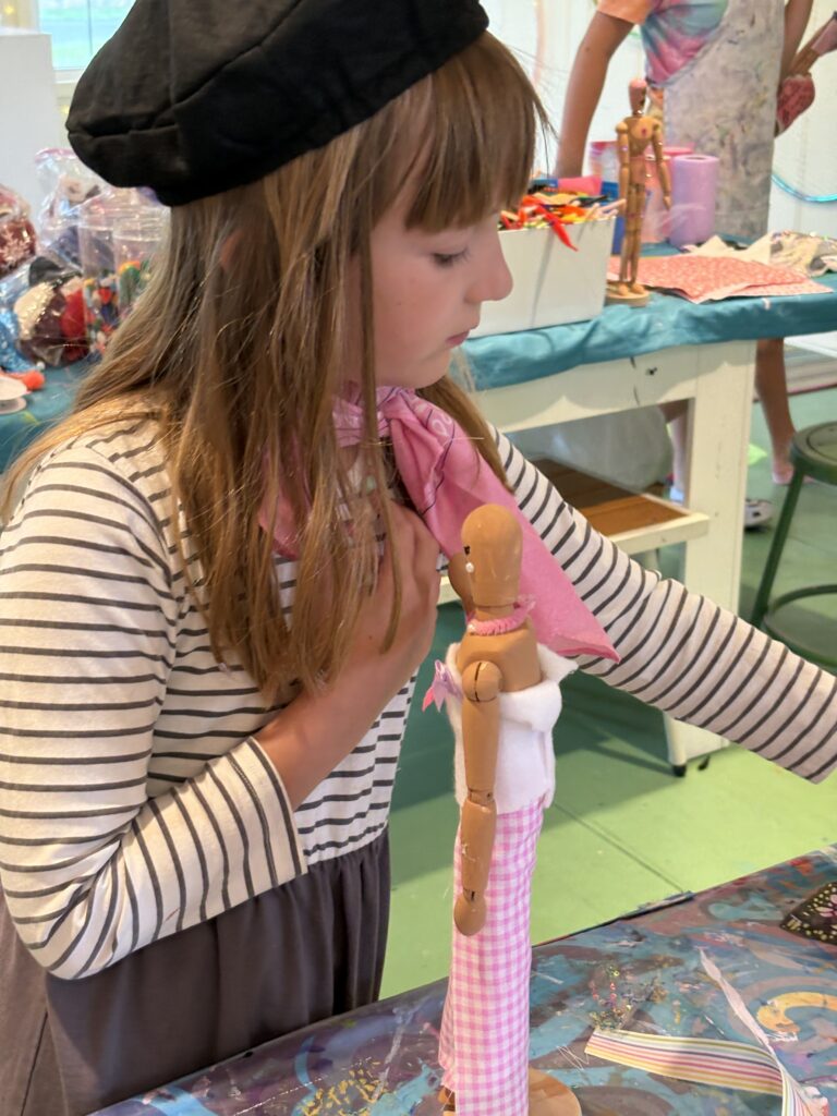 Young artist dressed in a French-inspired costume holding an Eiffel Tower sculpture during Paris Art Camp at Pink Art Pixie in Joppa, Maryland